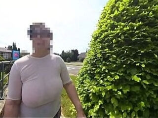 A busty natural milf walking in the street braless with transparent top.
